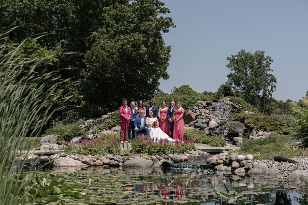 A group of visitors exploring a scenic rocky shoreline along Lake Champlain on a sunny summer day.