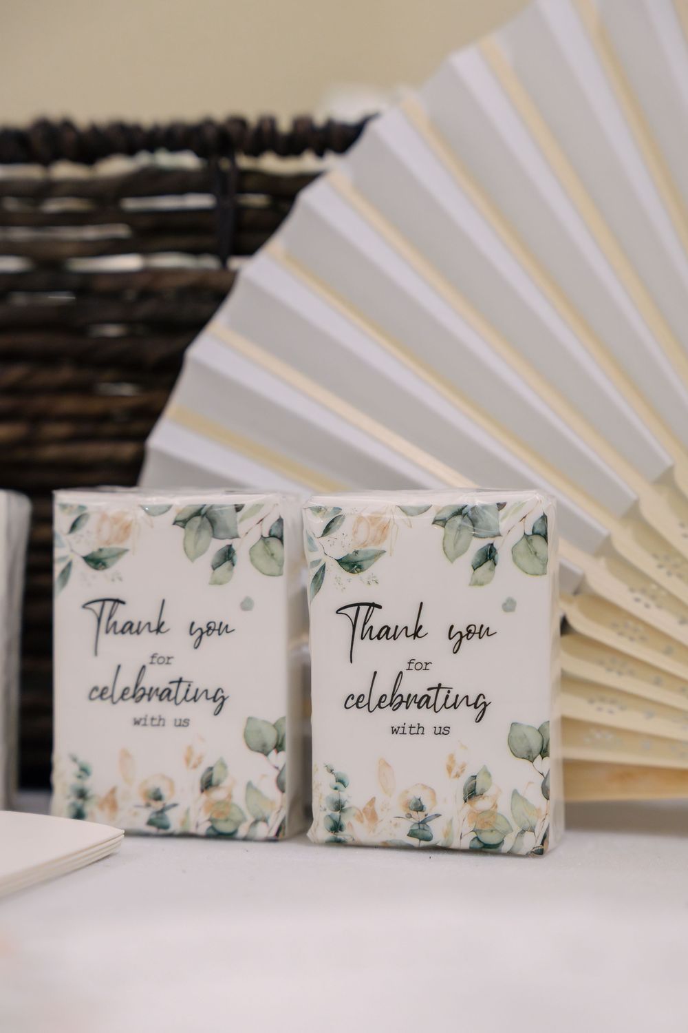 Floral thank you party favor boxes displayed with a white paper fan against a rustic wooden background.