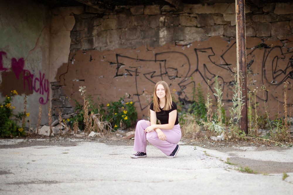 Woman in pink dress lying on ground against graffiti wall in urban setting.
