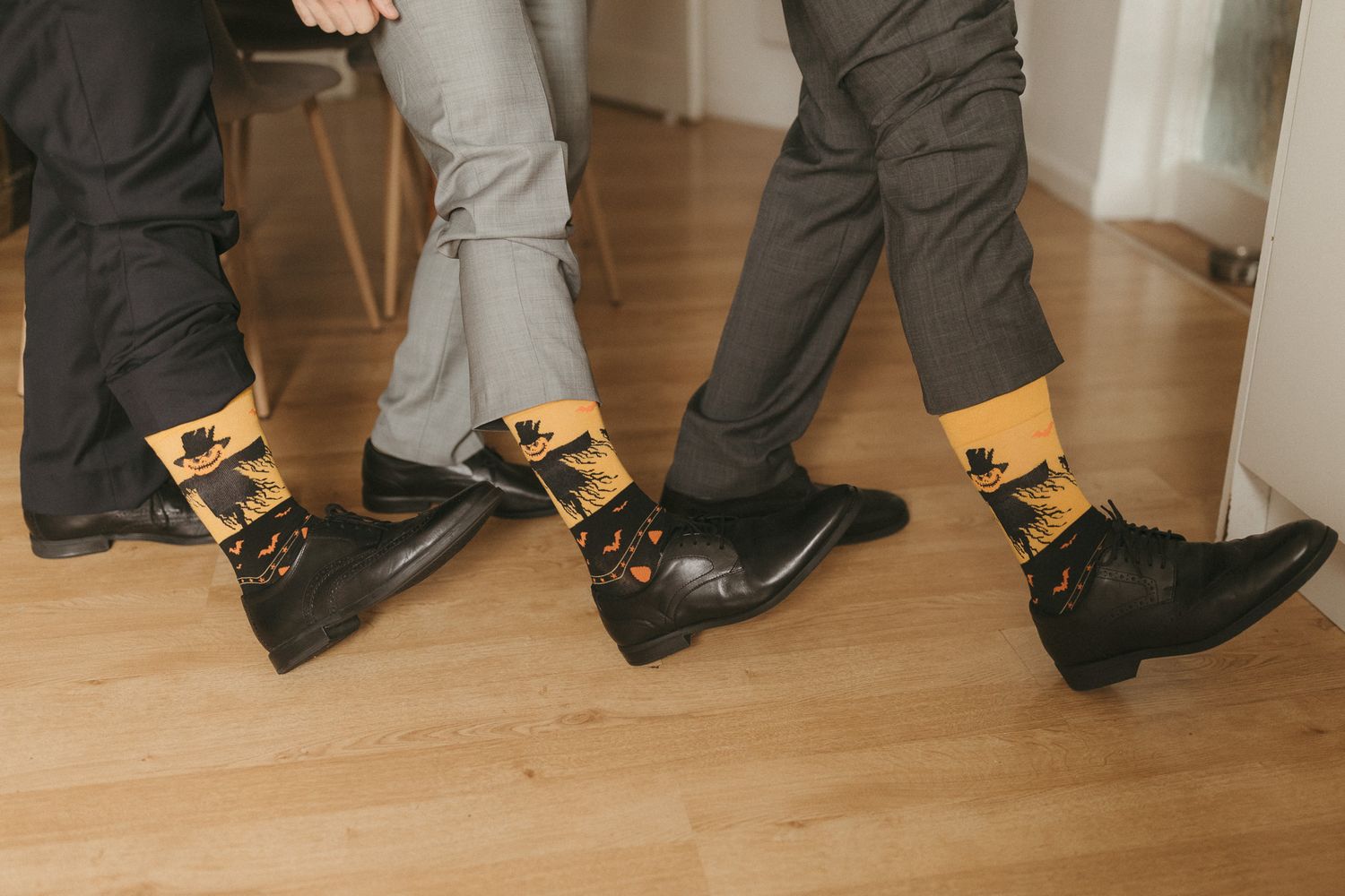 View of shoes and pant legs of people standing in line on a light hardwood floor.