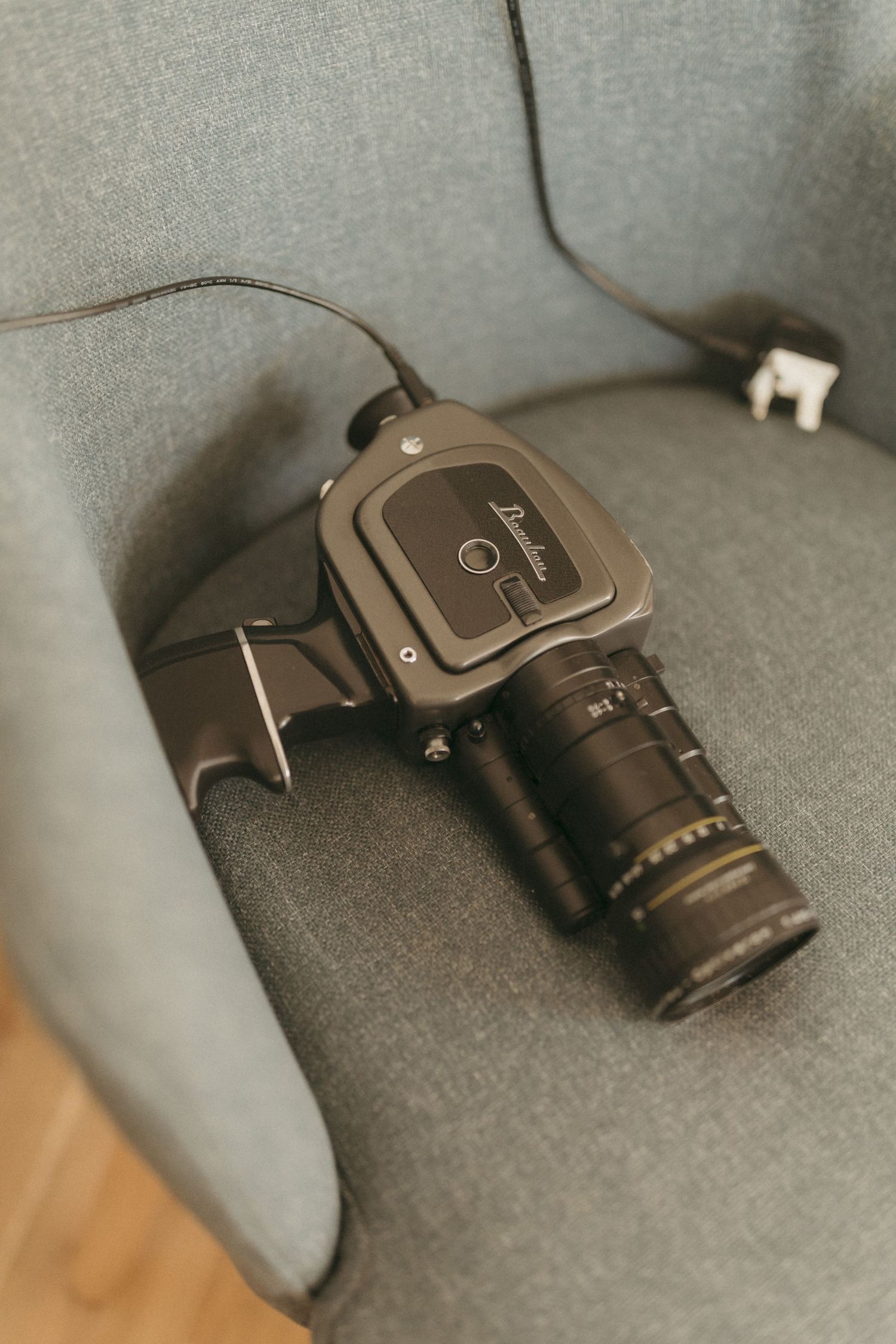 Professional camera with telephoto lens resting on gray fabric surface.