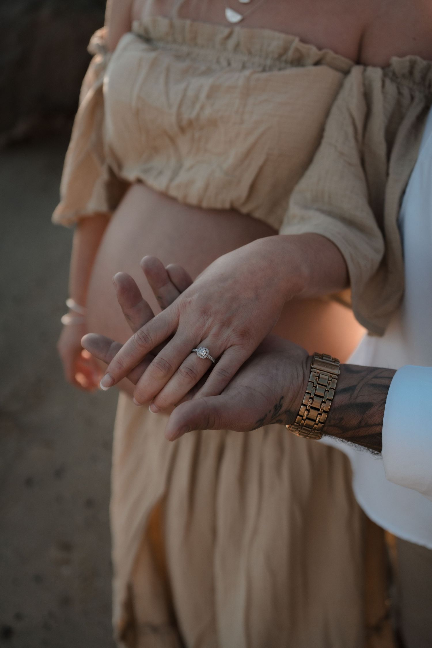 Elegant wedding rings shown in close-up detail on hands wearing beige attire.