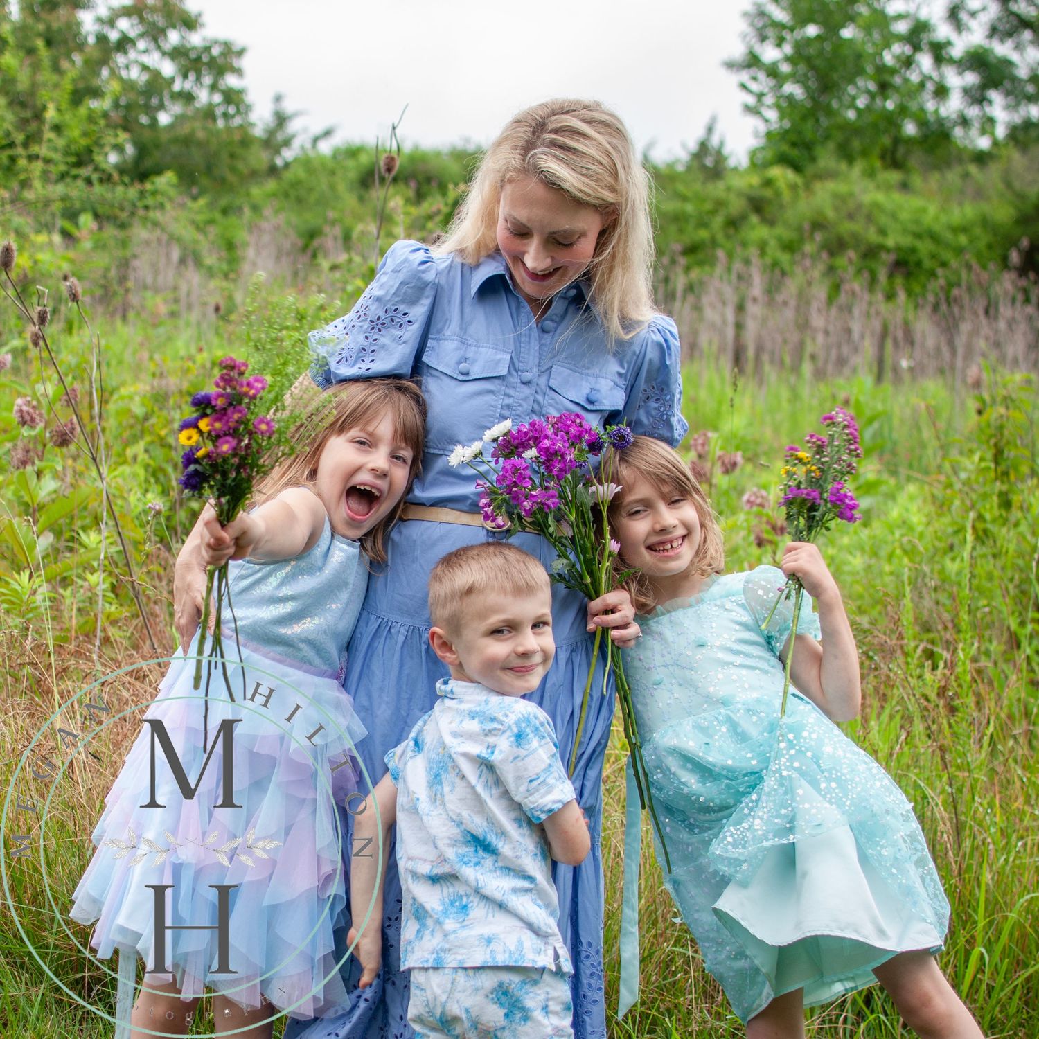 Image of a family playing together in a wildflower meadow showing joyful expressions and wearing light blue patterned clothing.