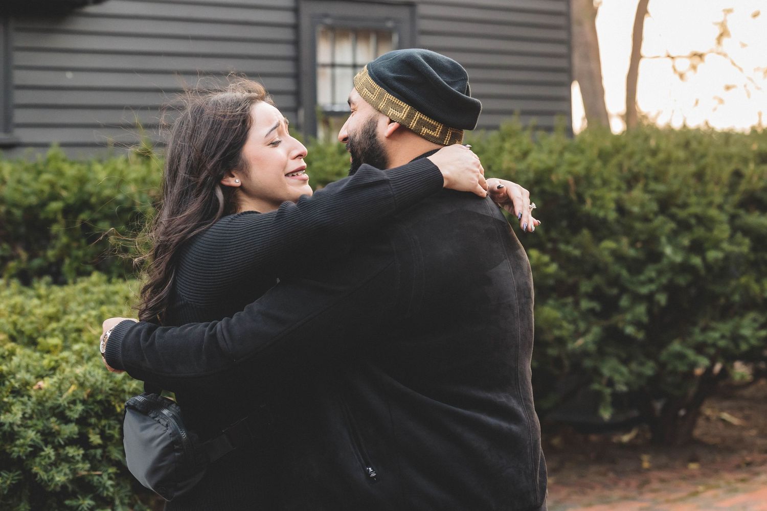 A joyful embrace shared between two people in dark clothing.