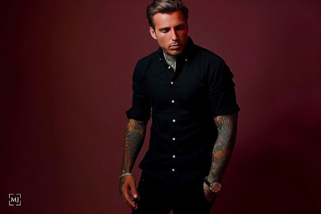 Moody studio photography of model in black shirt against dark red background.