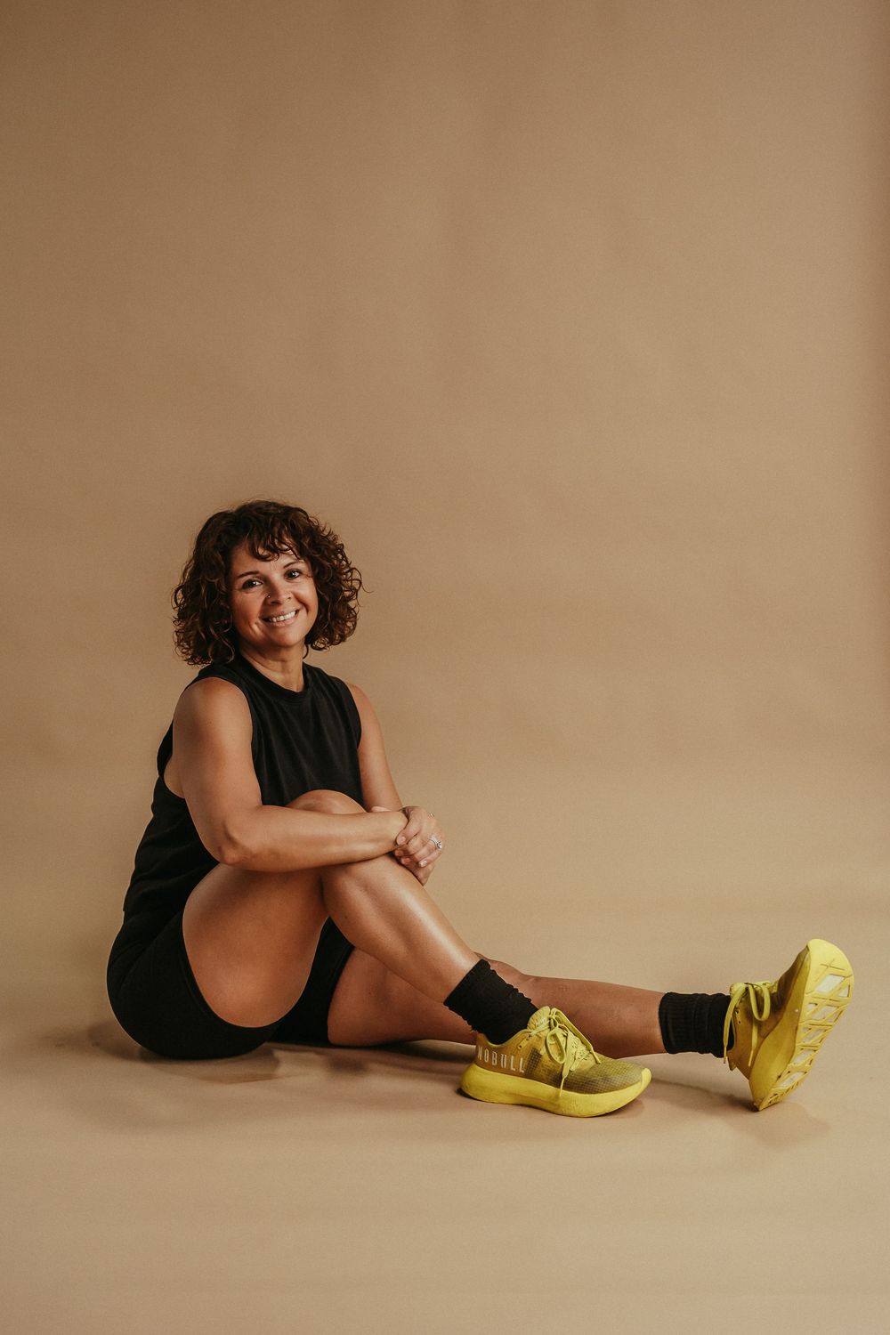 Series of artistic fashion poses showcasing bright yellow boots against neutral beige backdrop in studio setting.
