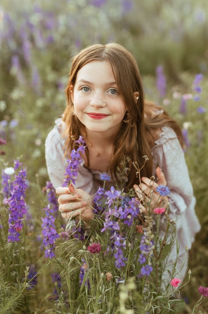 A dreamy summer portrait in a field of purple wildflowers with soft natural lighting and a whimsical mood.