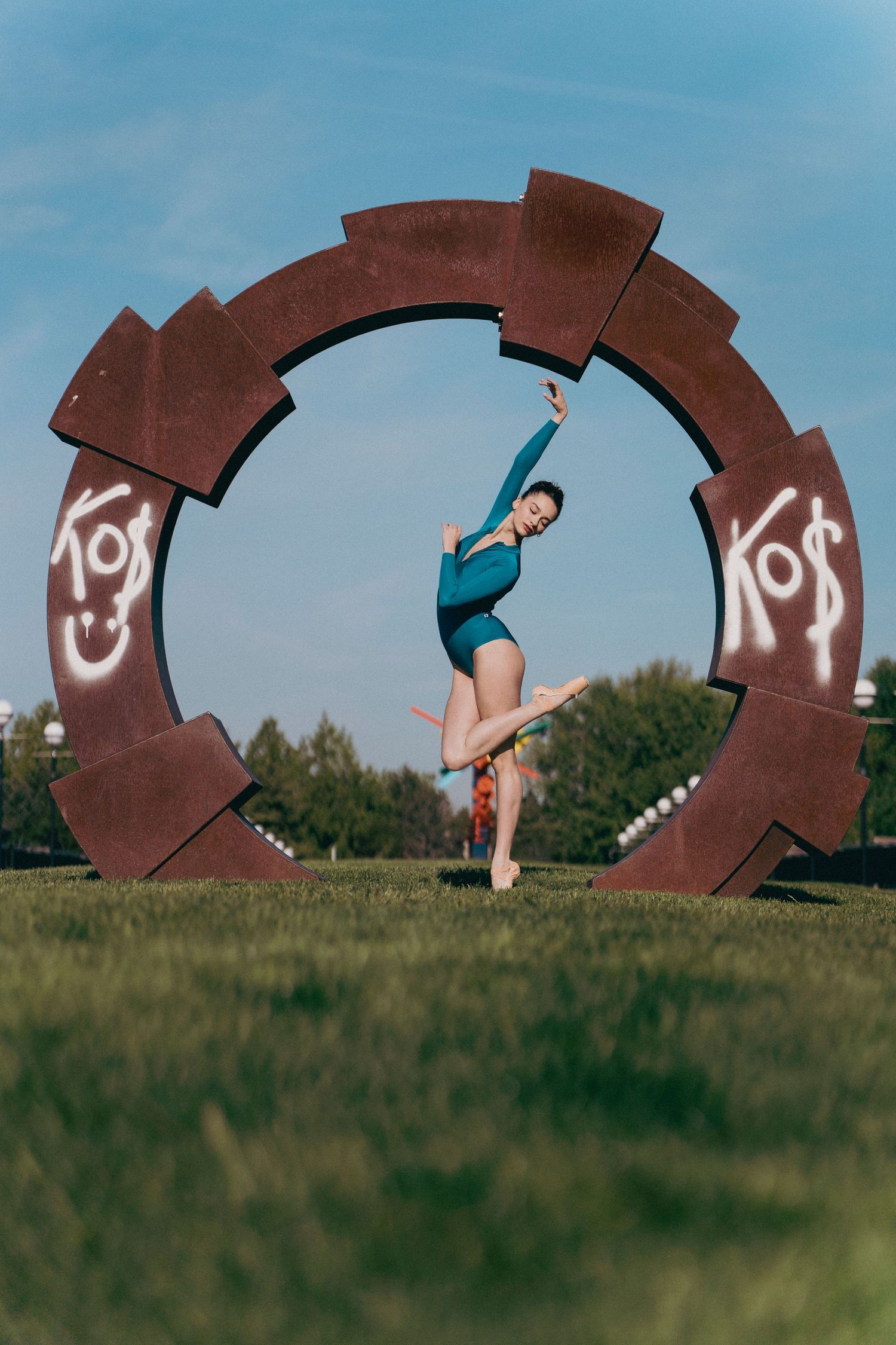 Photographer shooting a ballet dancer balancing en pointe in early morning light with lush greenery background Indy Ballet Photographer