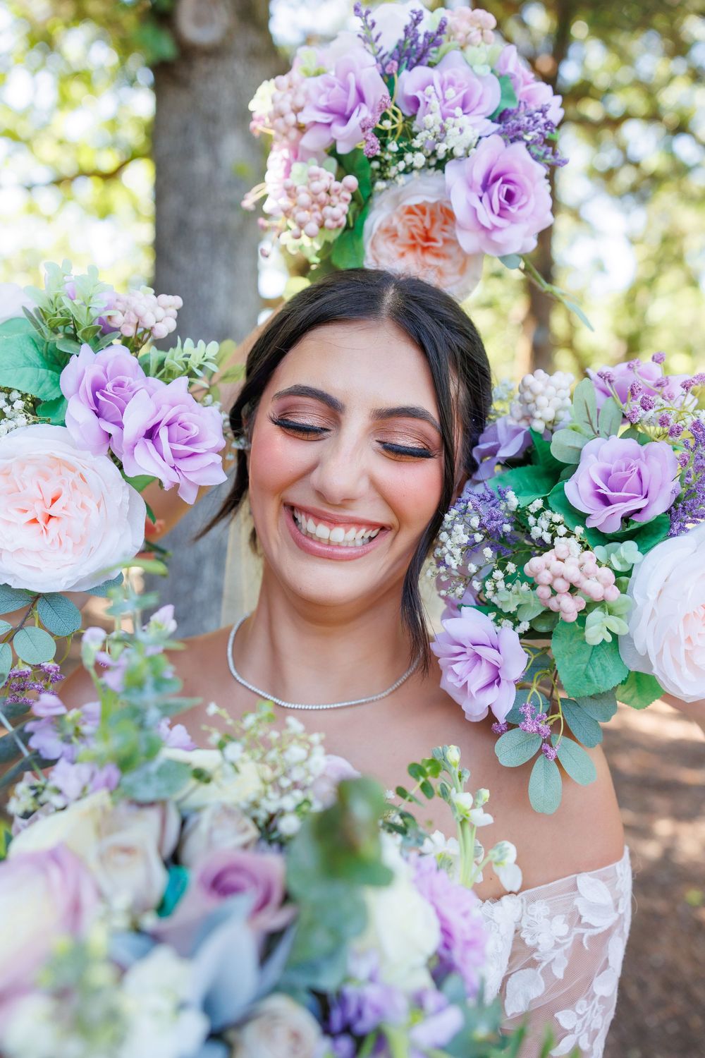 Romantic floral crown with purple and pink roses adorns a dreamy outdoor bridal portrait.