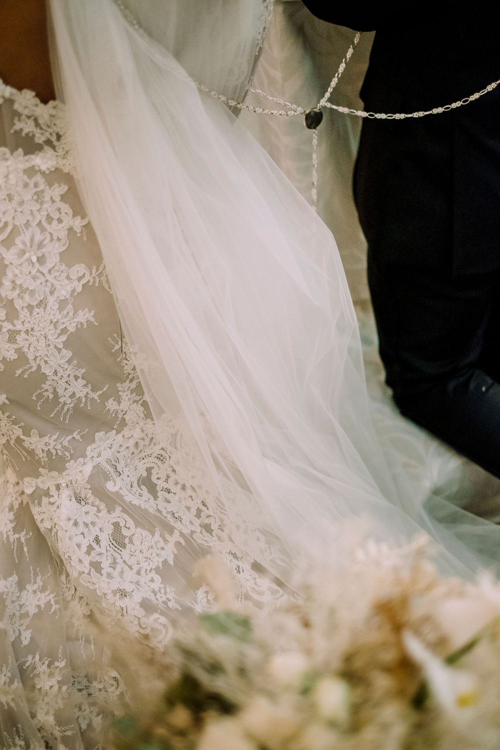 Close-up detail of delicate lace trim and soft tulle on a white wedding dress veil.