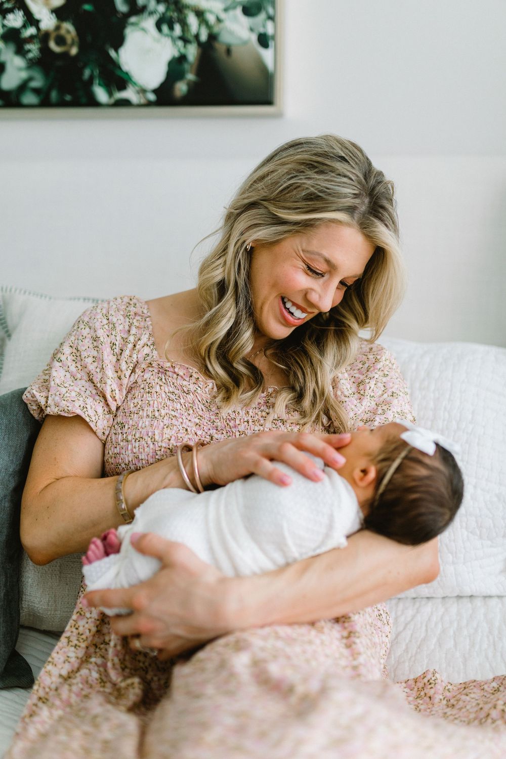 A tender moment between parent and newborn as they share joy and laughter on a white couch.