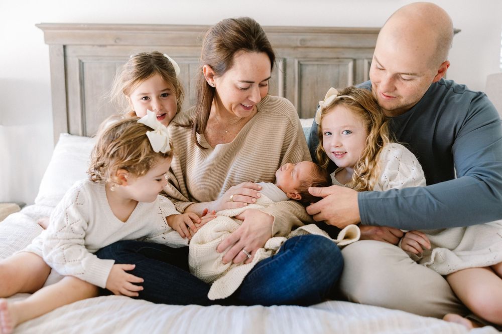 Happy family sits together on bed while meeting their newest addition.