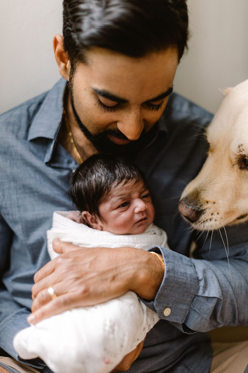 Sweet family moment with newborn and white dog meeting for first time.