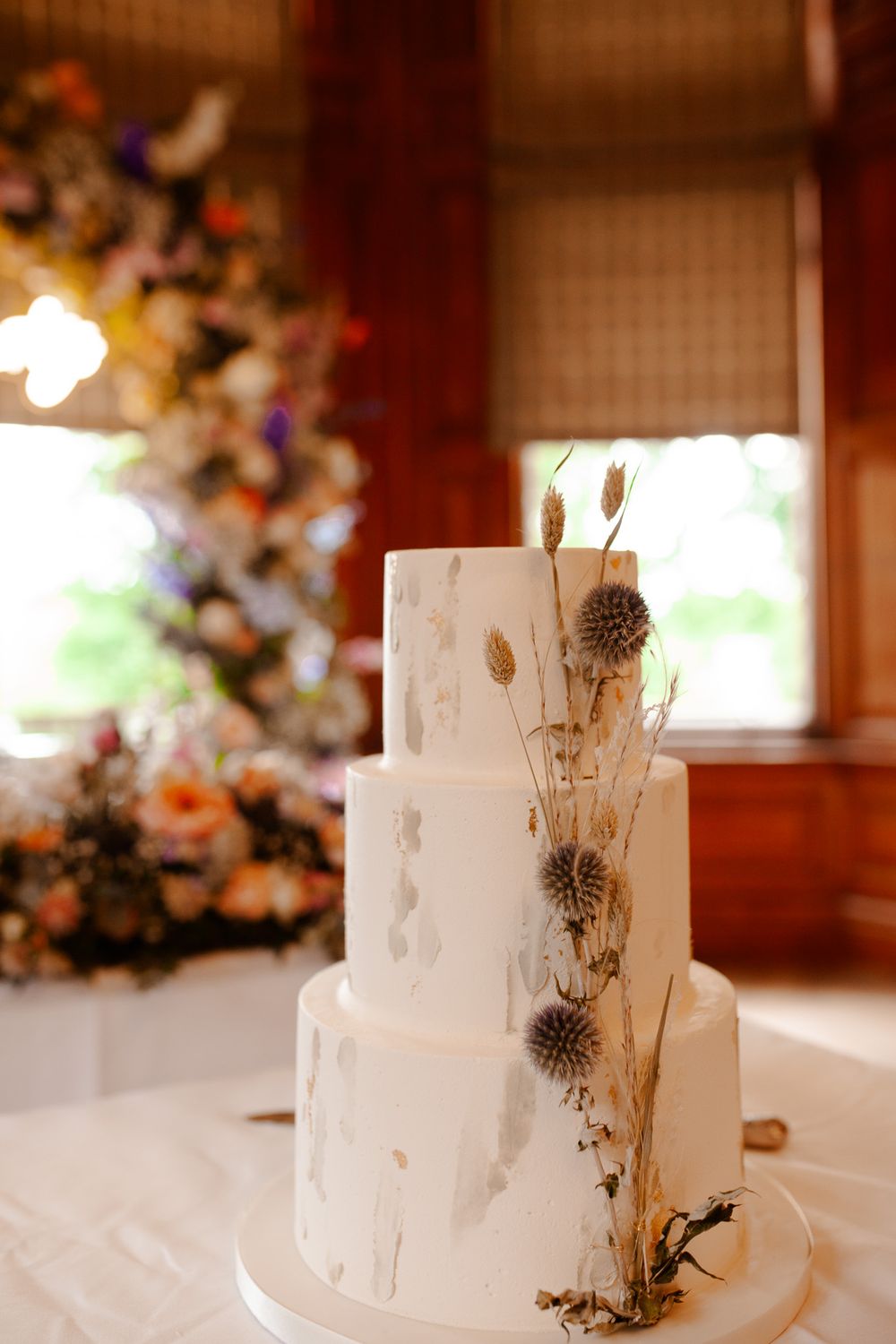 An elegant three-tiered white wedding cake decorated with dried flowers and botanicals.