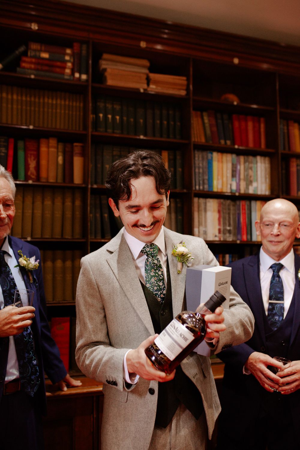 Groomsmen in light gray suits reading letters in a library setting.