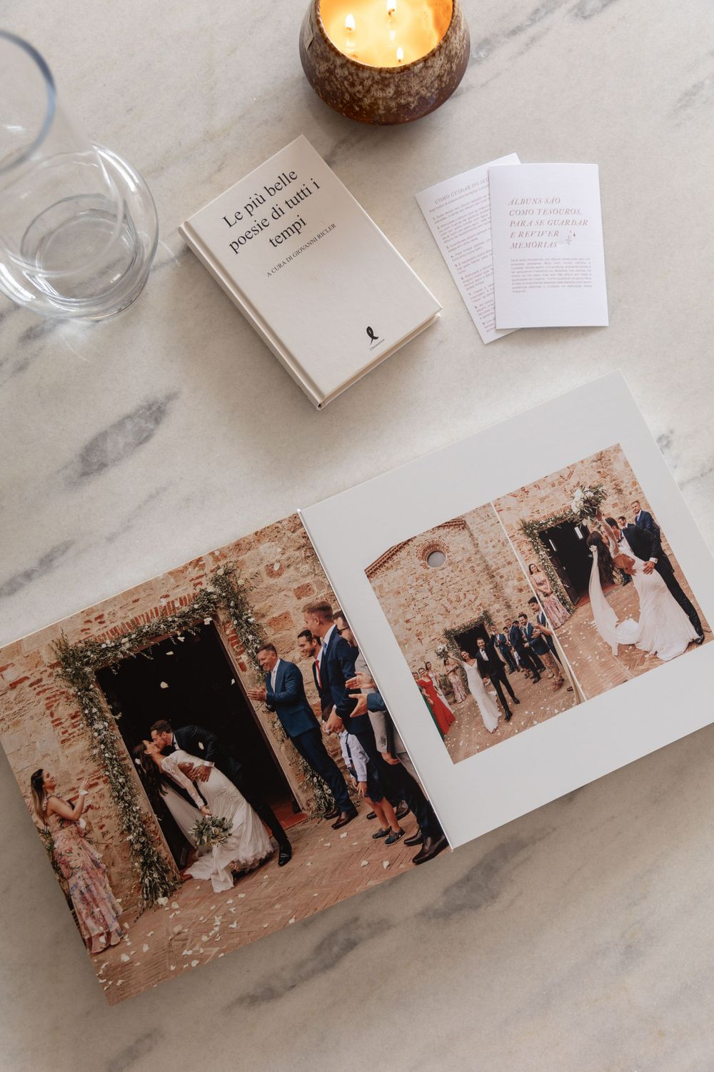 Wedding photo album layout with lit candle and book on marble surface showing ceremony photos.