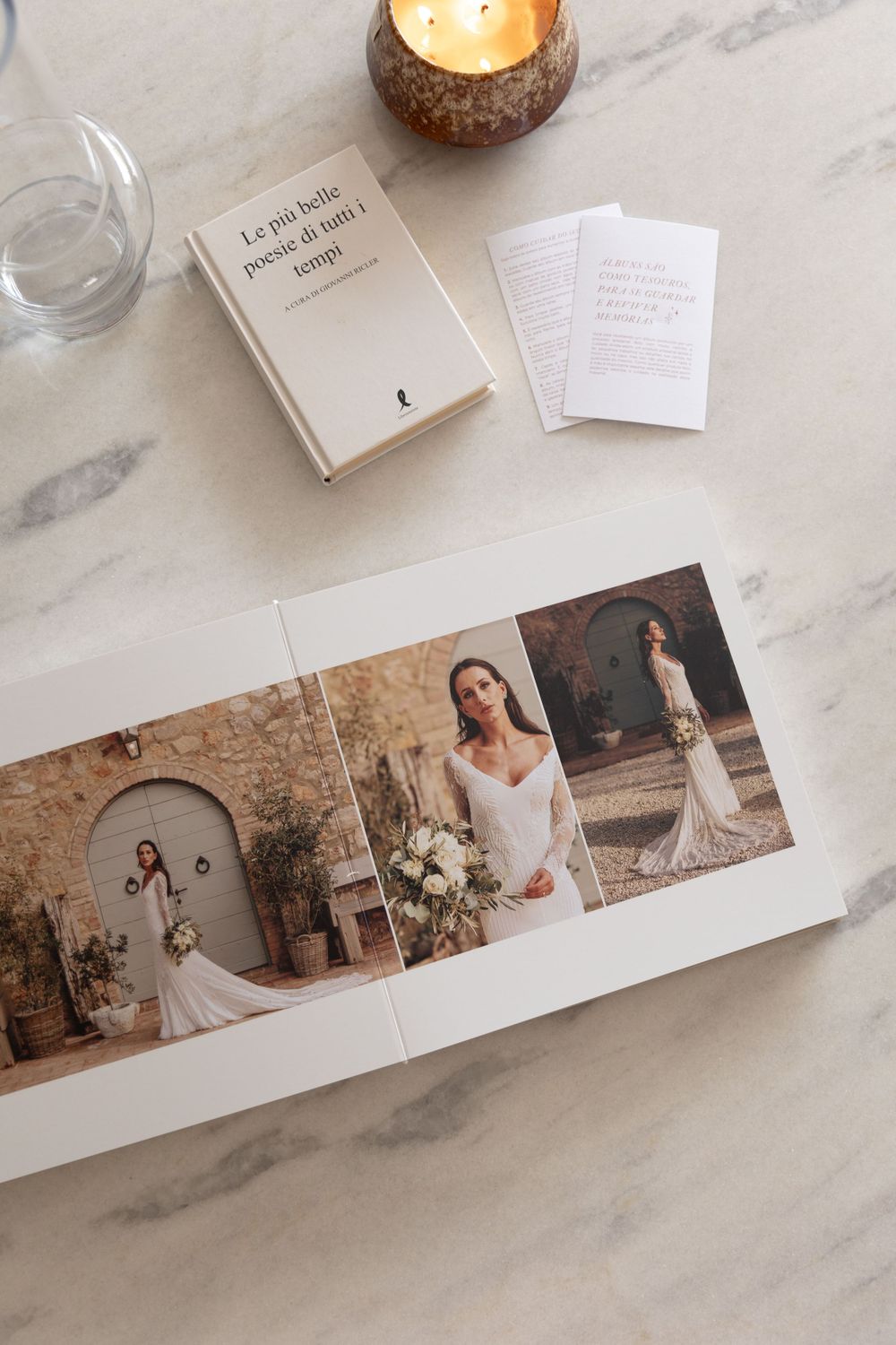 Wedding photo album displaying bridal portraits against rustic stone wall backdrop.