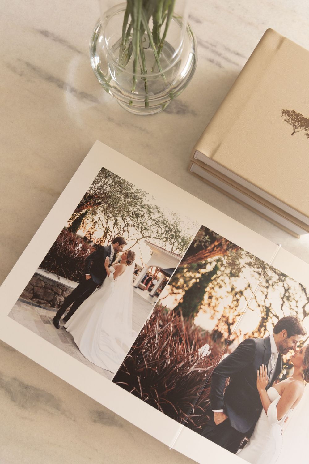 Open wedding album showing romantic ceremony moments with glass vase and books in frame.