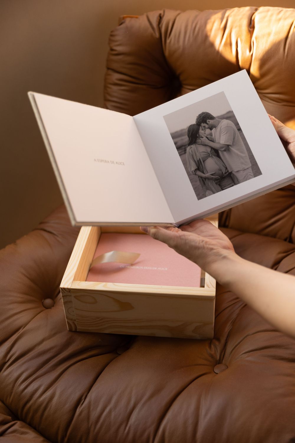White photo album open on leather chair displaying black and white portrait photography.