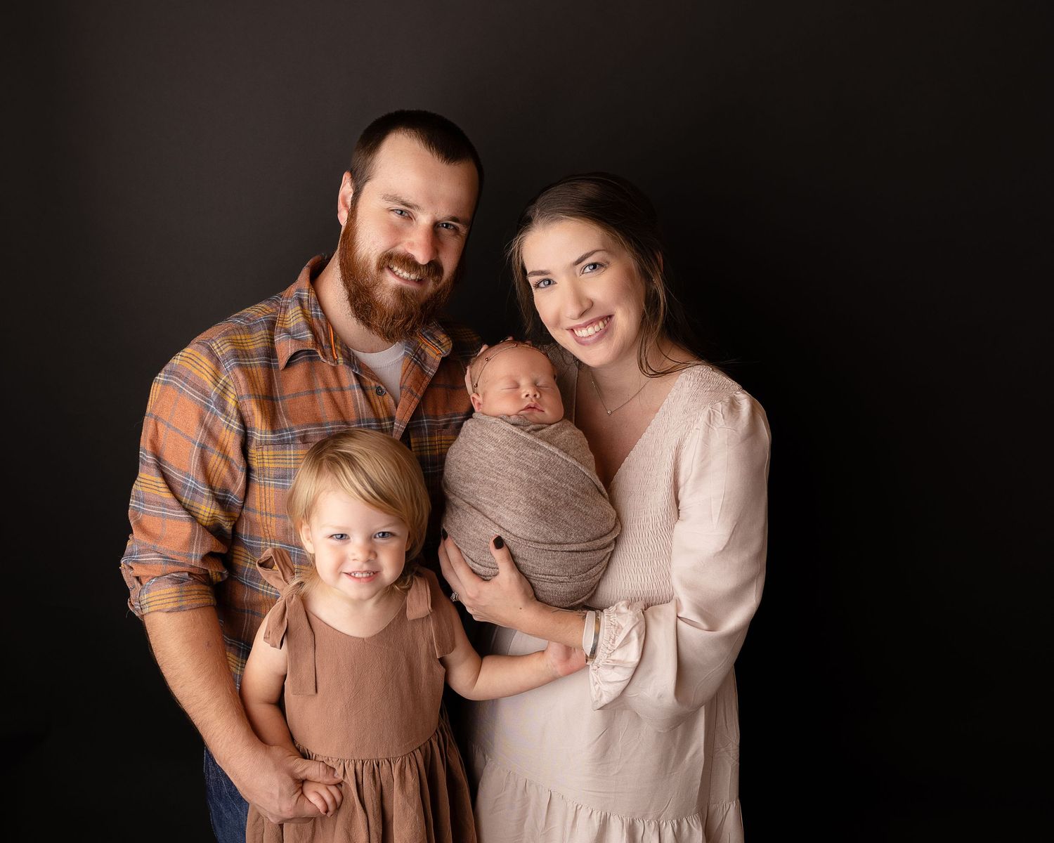 Professional photo of a newborn baby with her mother, father, and big sister