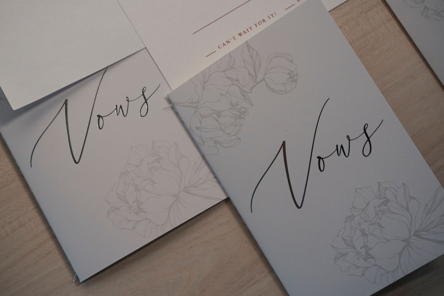 Two elegant vow books with minimalist floral design and cursive text.