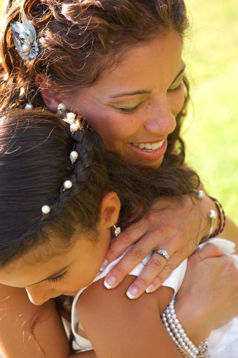 Two women sharing an intimate embrace with decorative pearl hair accessories and rings on display.
