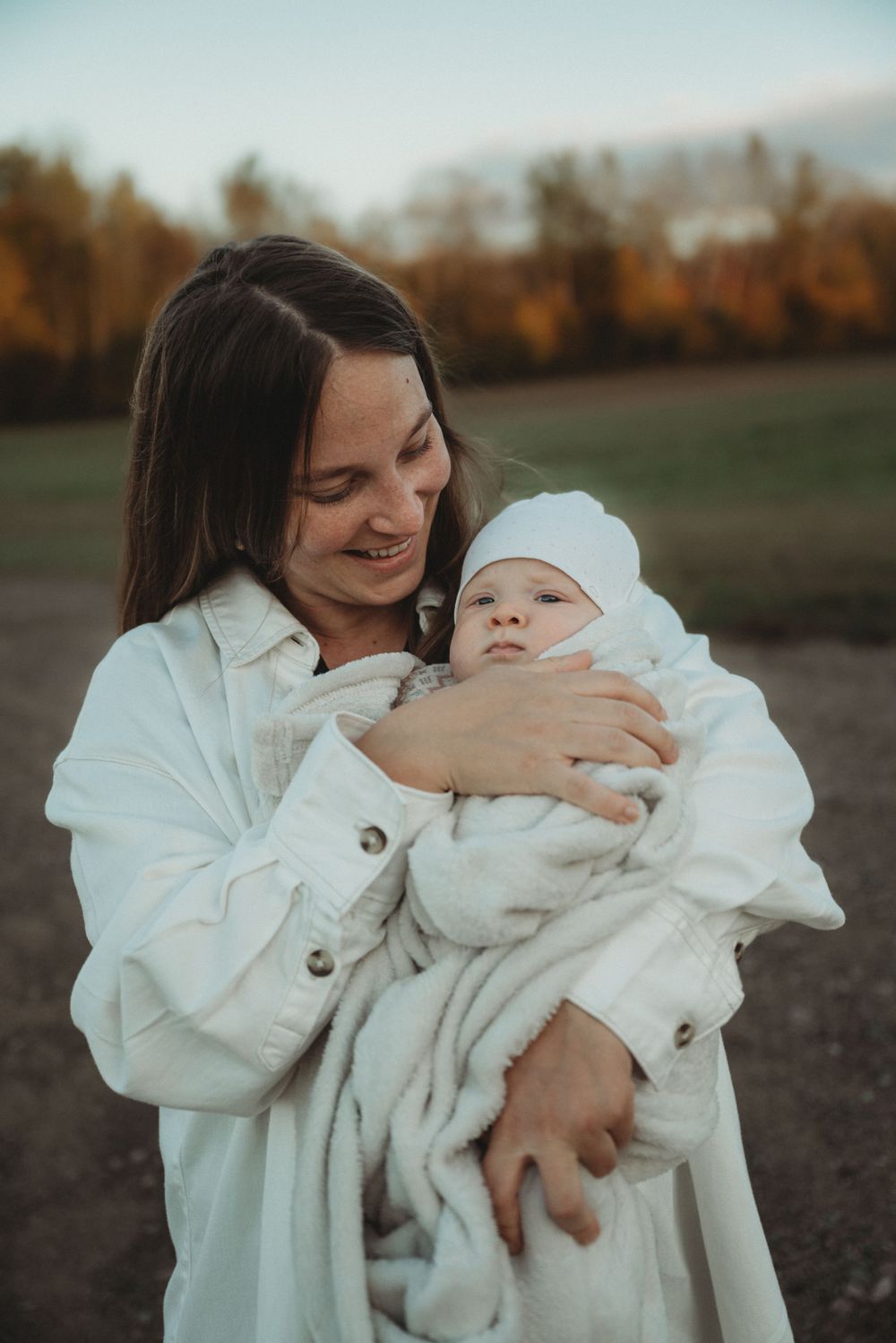 Parent sharing joyful moment with baby in white clothing outdoors.