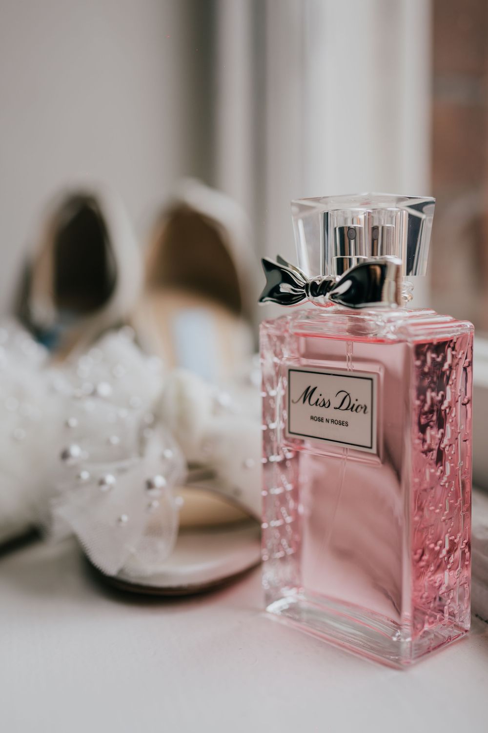A series of pink Miss Dior perfume bottles arranged artistically on a white surface with soft bokeh effects.
