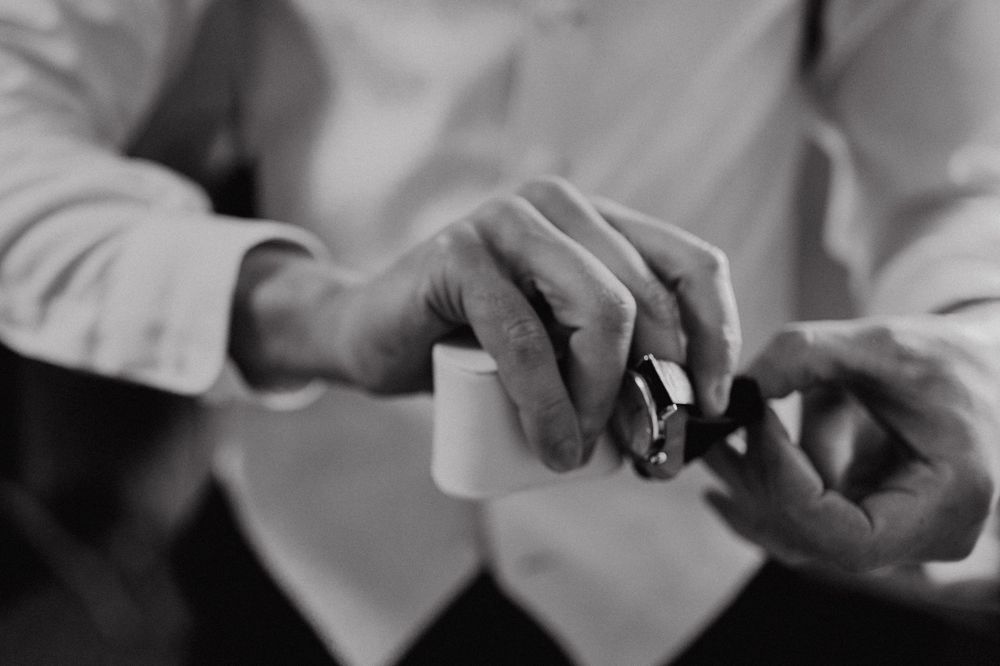 Close-up black and white photo of hands holding and adjusting a small object in soft focus.