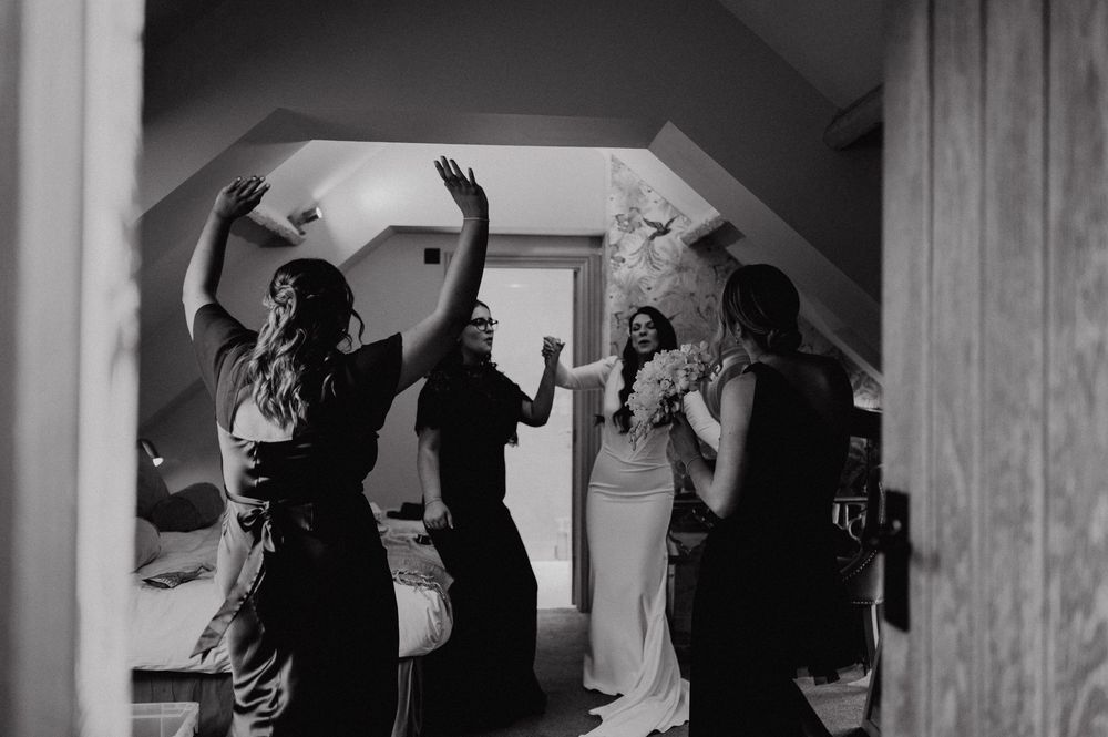 Black and white photograph of silhouettes celebrating and dancing together in a bedroom setting.