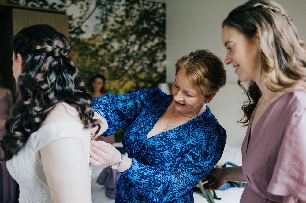 Intimate wedding preparations capture joyful moments and laughter shared between people wearing elegant blue and pink dresses.