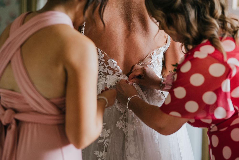 Wedding preparations at a bridal suite with white robes and polka dot dresses visible in detail shots.