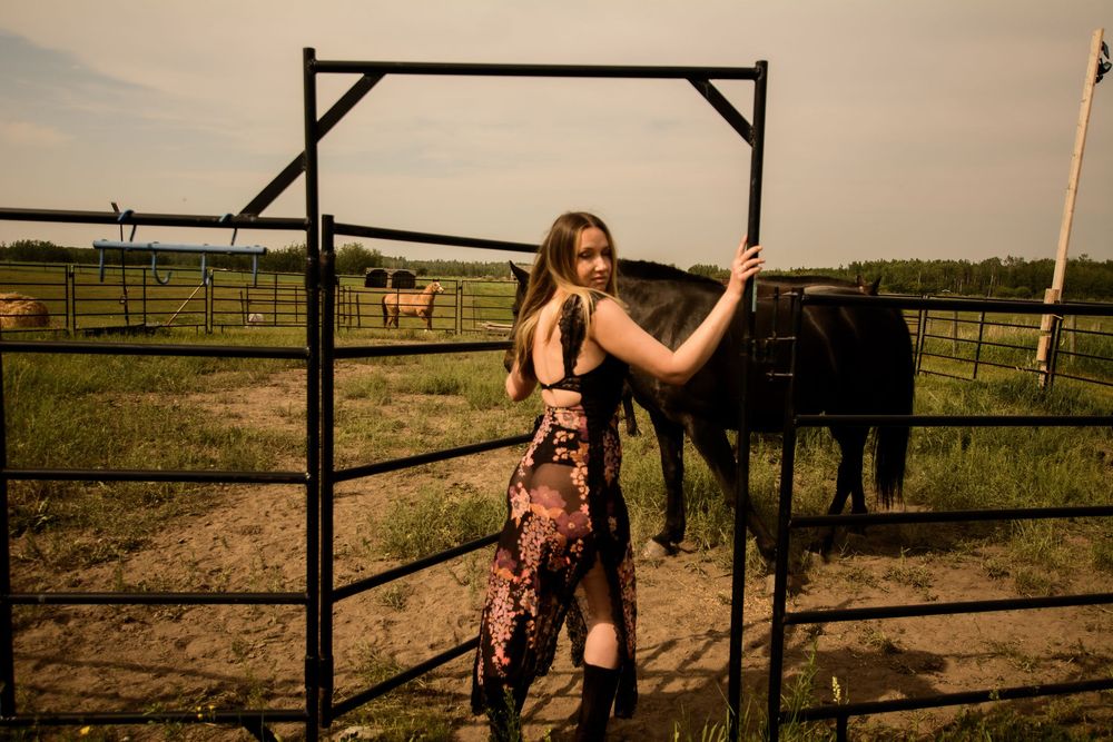 Artistic photoshoot featuring silhouettes against fence posts in a rural setting.