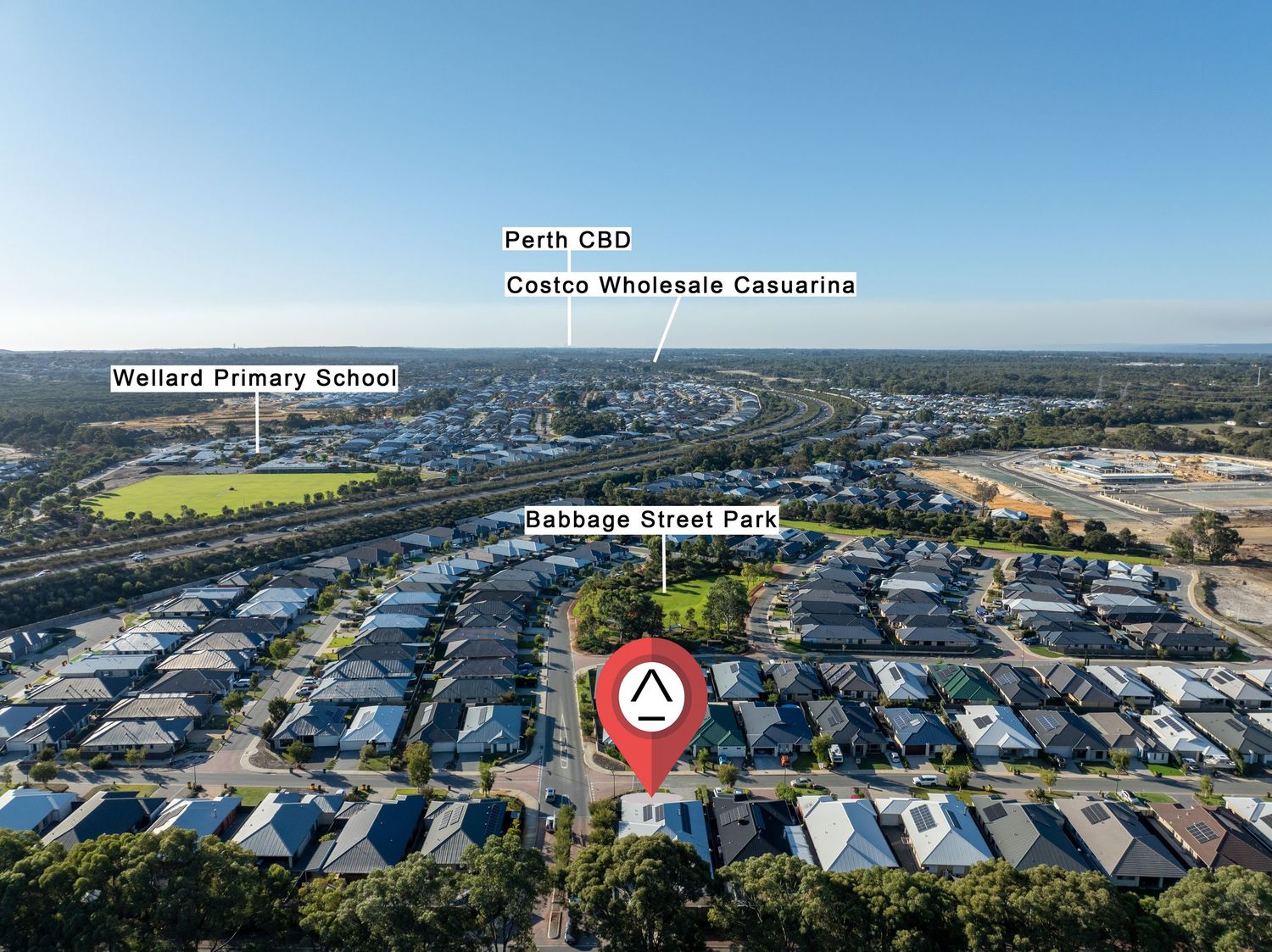 Aerial view of residential housing development with sports field and shopping centers visible in suburban neighborhood.
