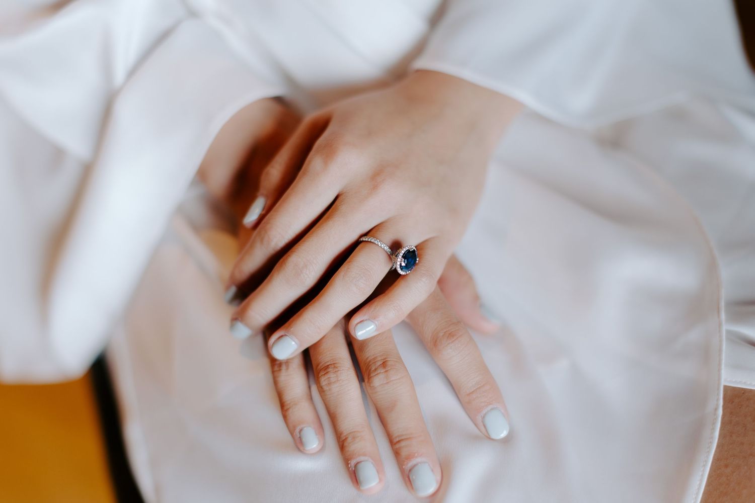 Close-up shots of hands showing delicate engagement rings in natural light.