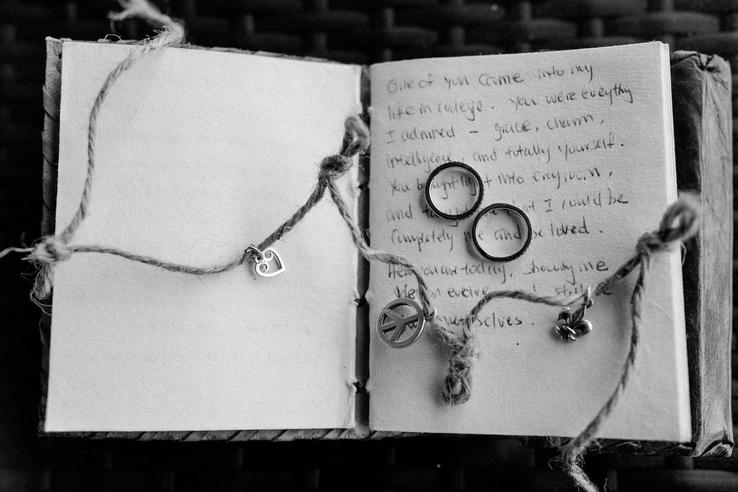 Black and white photographs of wedding rings next to handwritten notes in a journal.
