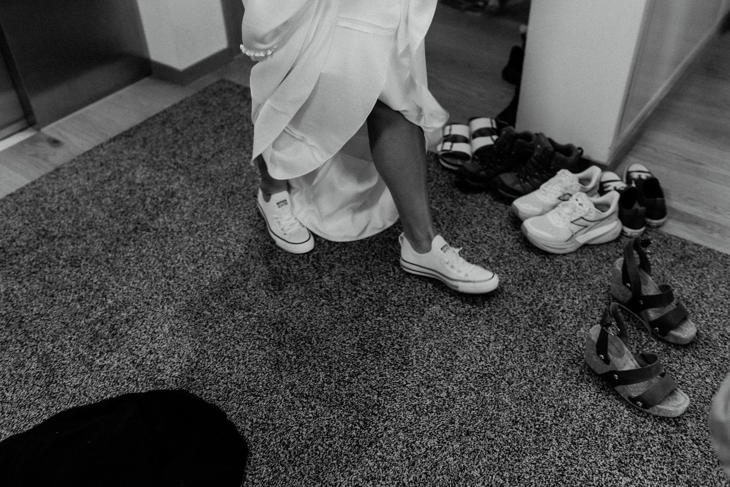Wedding guests' formal shoes lined up on gray carpet at a celebration event.