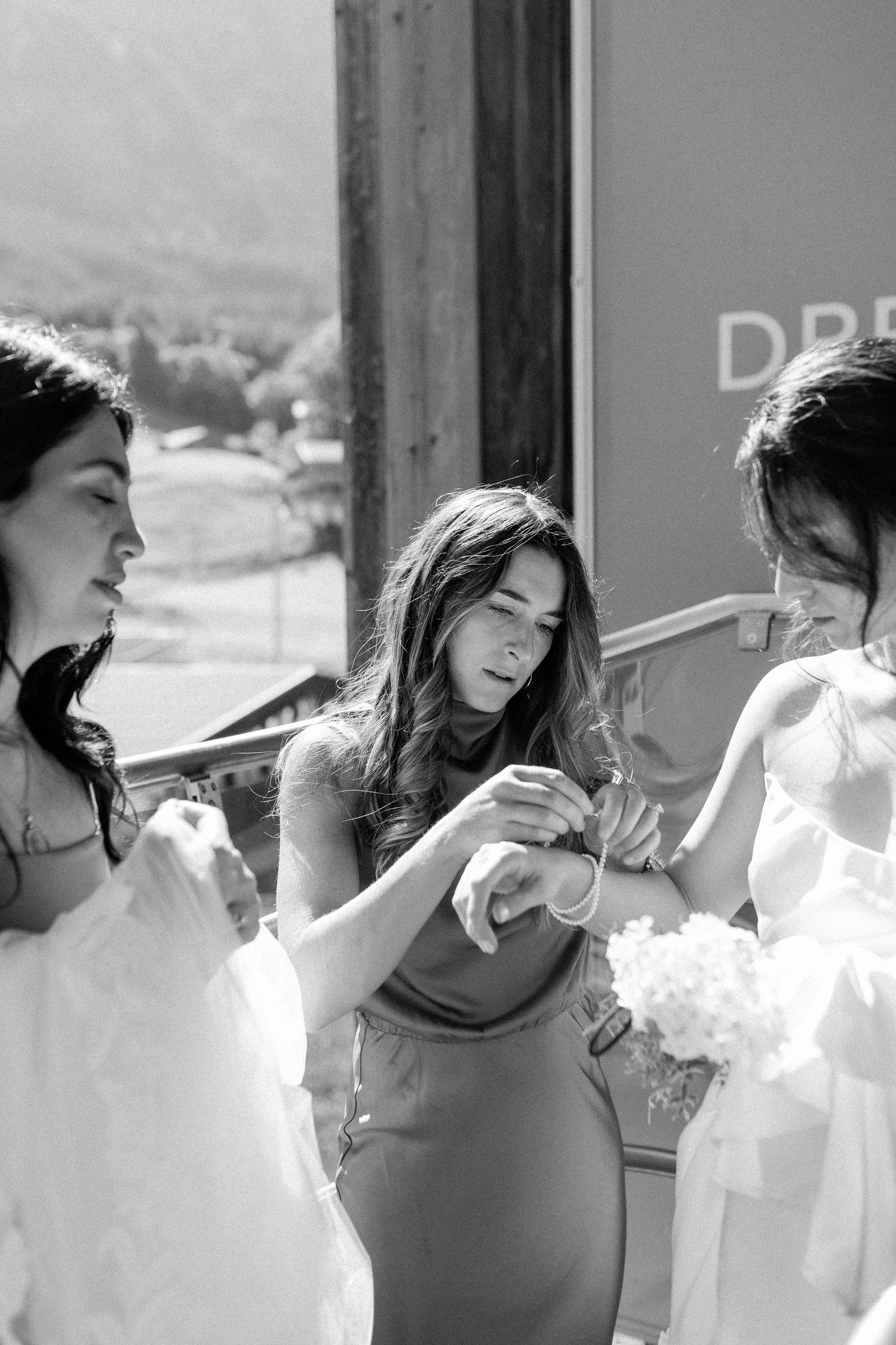 Bridesmaids share a joyful moment while getting ready in black and white photography.
