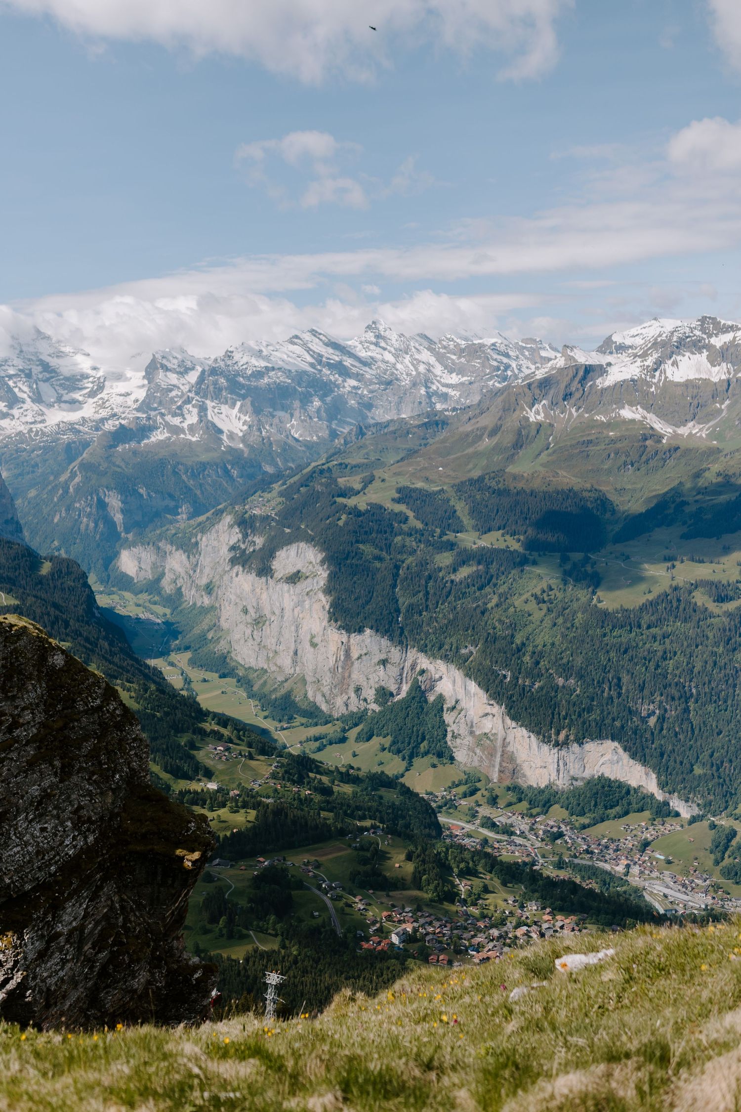 Scenic mountain landscape overlooking a valley with snow-capped Alpine peaks and green meadows in Switzerland.