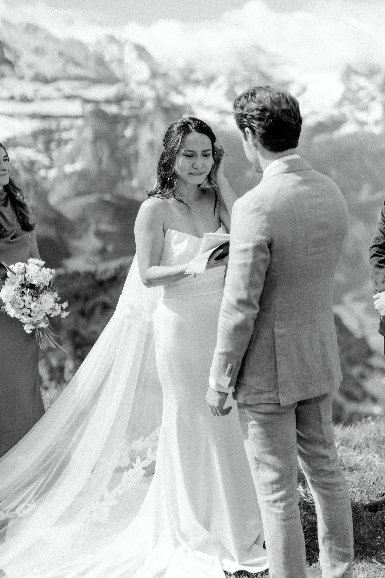 Couple exchanging vows during mountain wedding ceremony with dramatic alpine peaks in background.