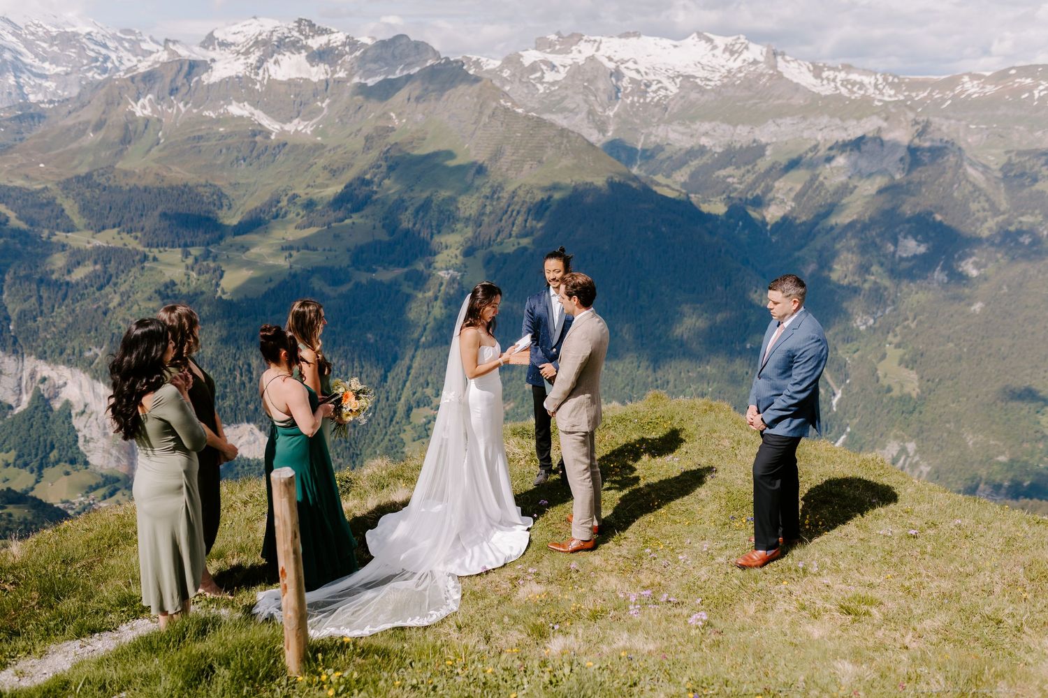 Wedding celebration group gathered on scenic mountain overlook with stunning alpine vista.