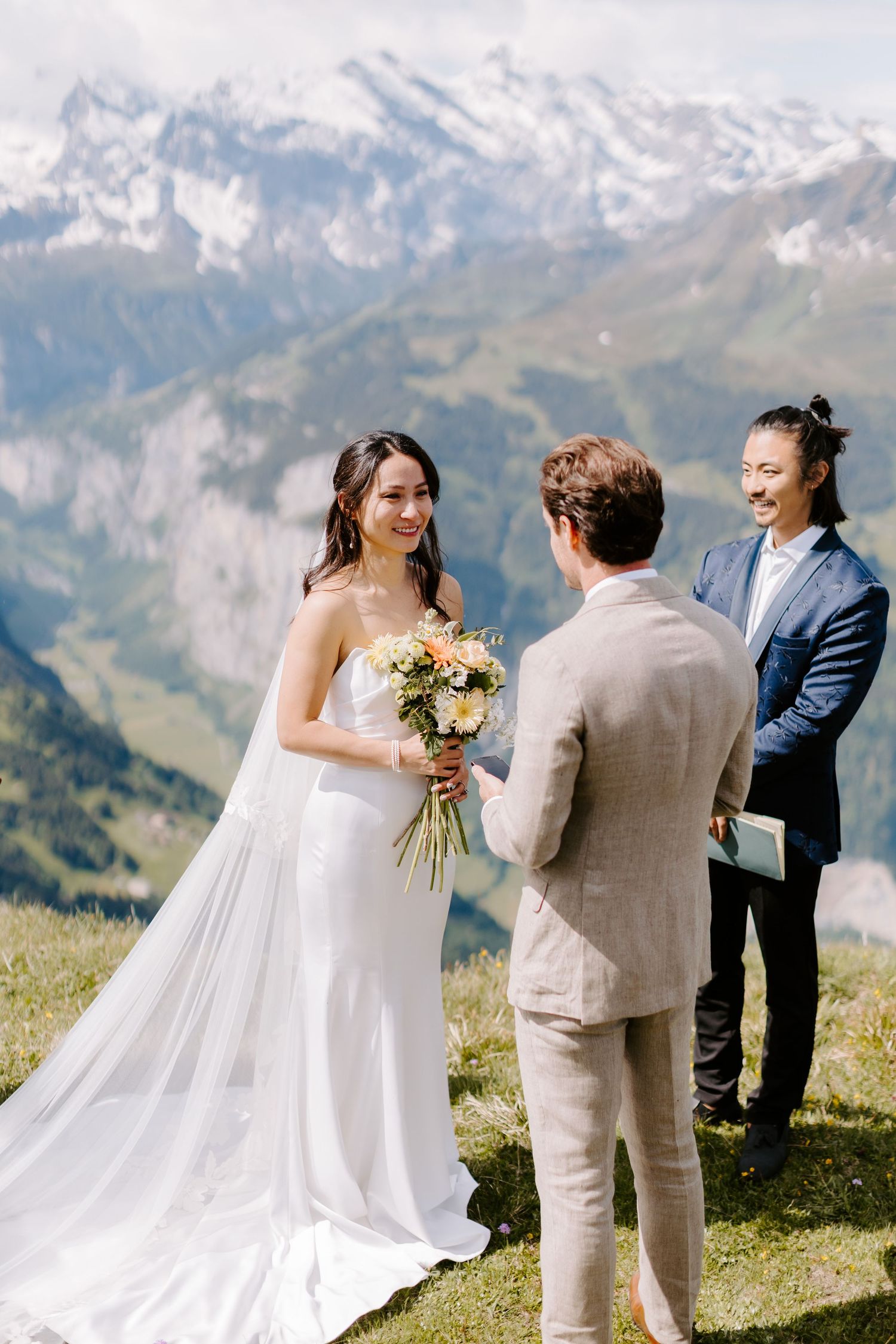 An intimate mountain wedding ceremony takes place with snow-capped peaks in the background.
