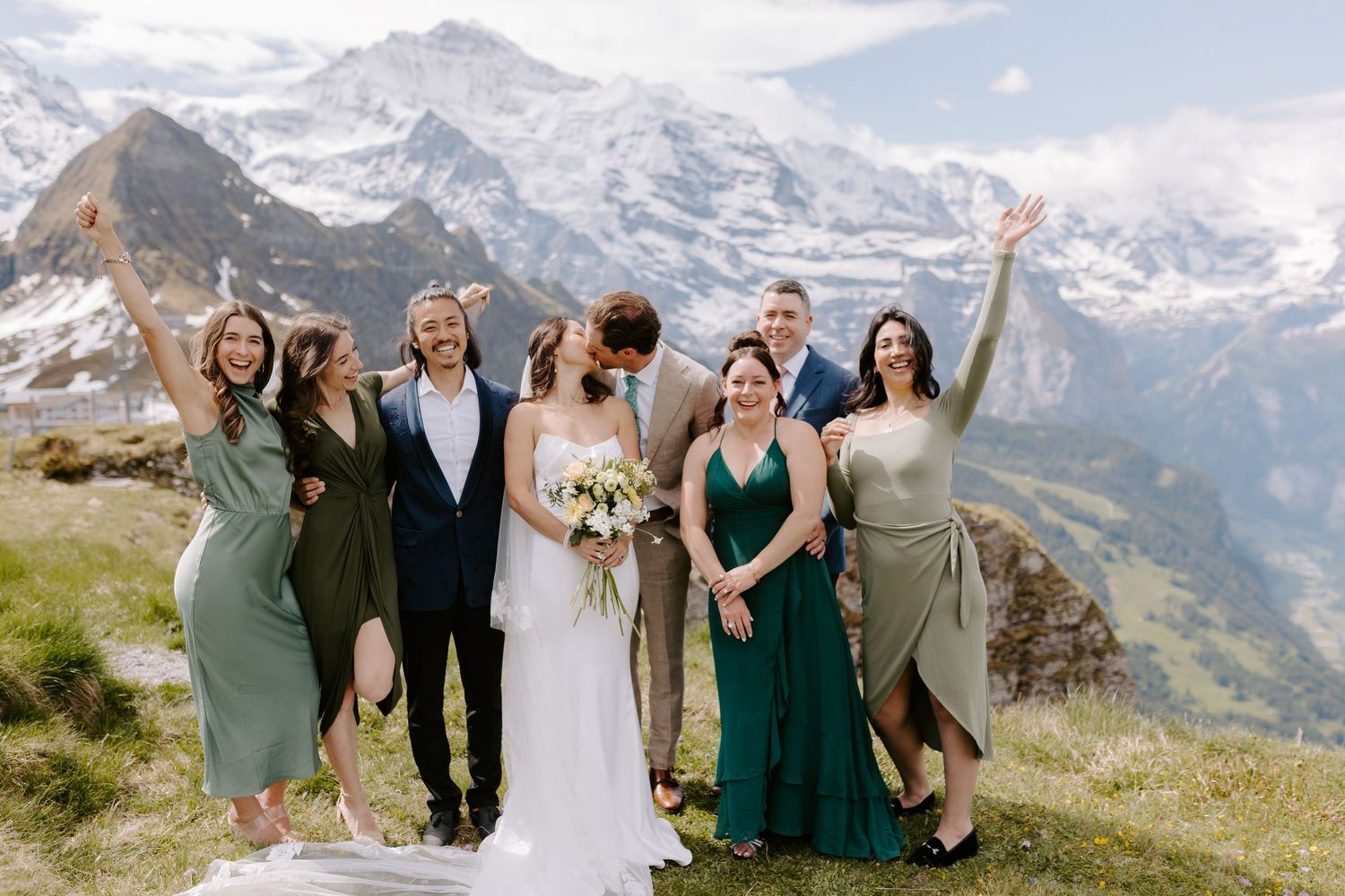 Joyful celebration group posing together with snow-capped mountain peaks in background.