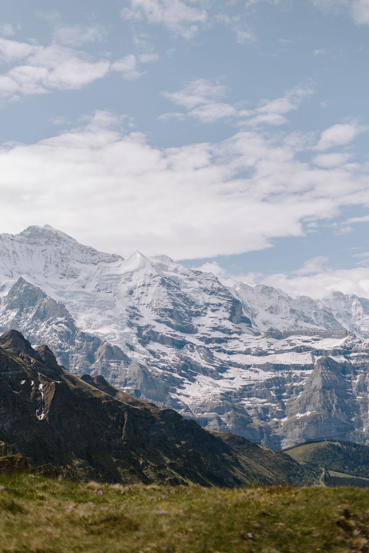 Majestic snow-capped Swiss Alps mountain range under blue sky with wispy clouds.