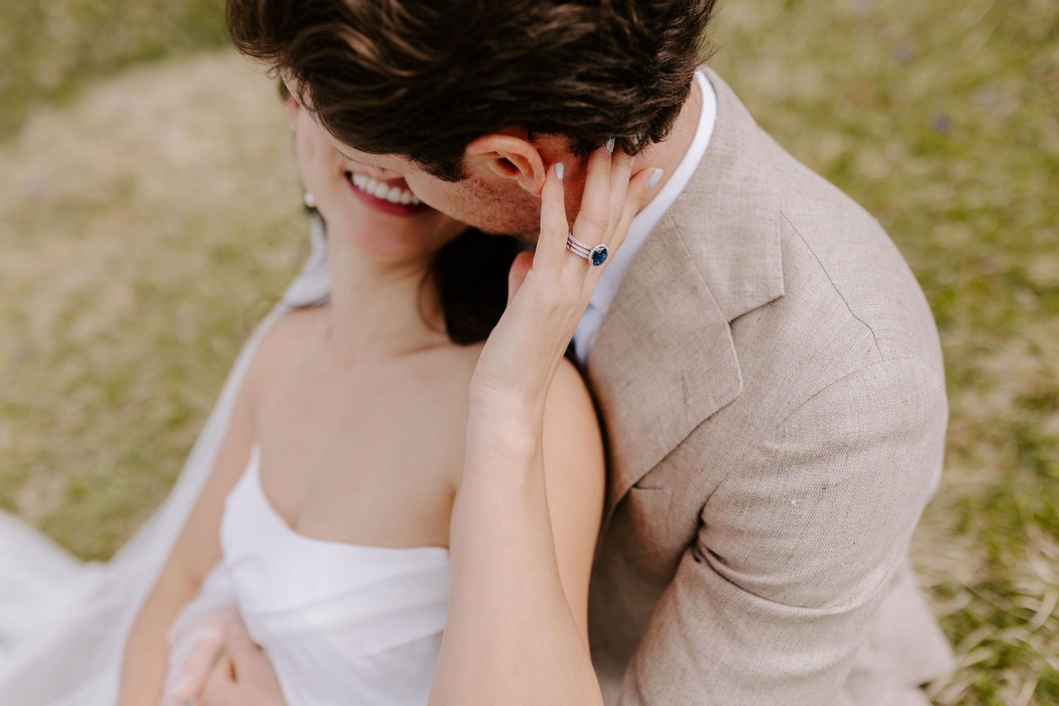A romantic couple in wedding attire embraces outdoors in a garden setting during their special day.