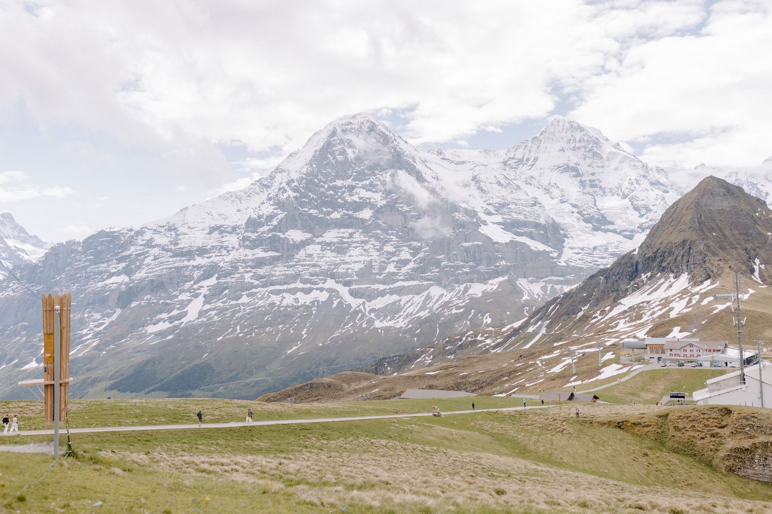 Panoramic view of snow-dusted mountain range with hiking trail in foreground.