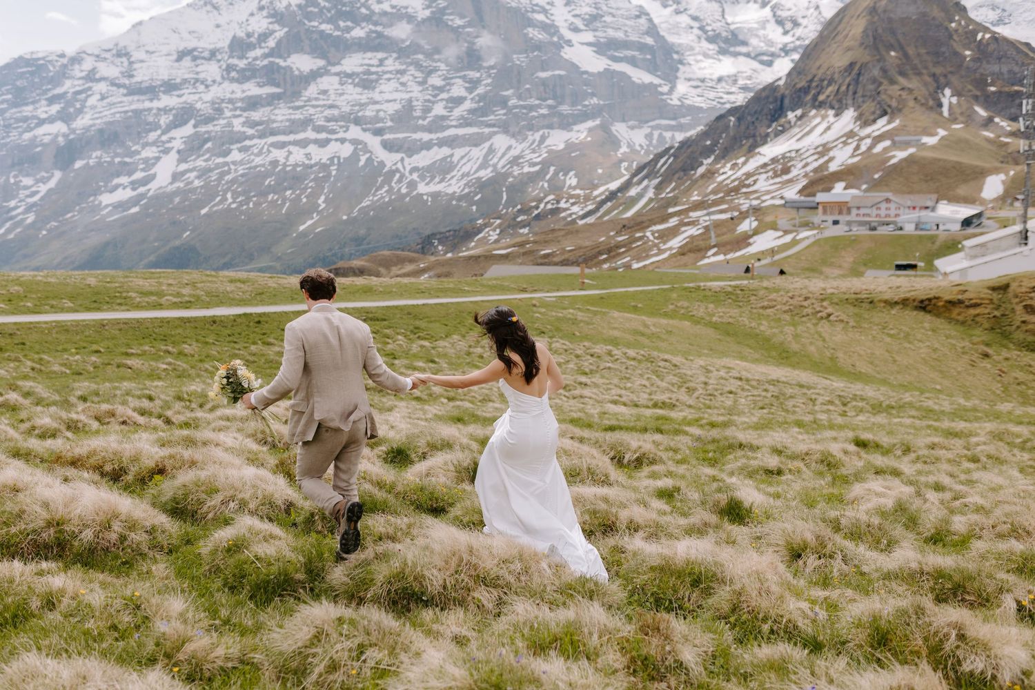 Scenic wedding photography session against rugged Swiss Alps landscape with flowing white bridal gown.