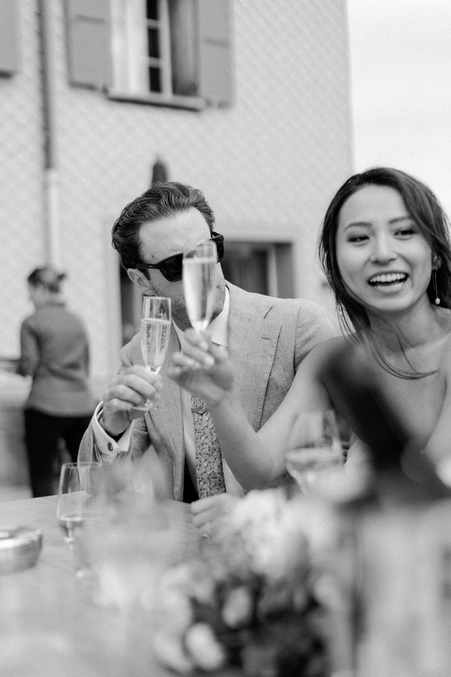 Guests enjoying champagne and laughter during an outdoor celebration at an elegant reception.