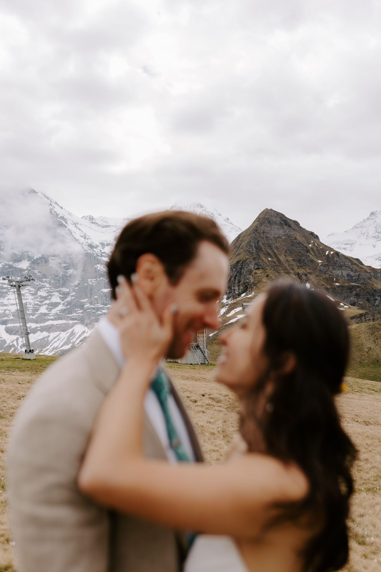 A couple sharing a romantic moment against a backdrop of snowy mountain peaks.
