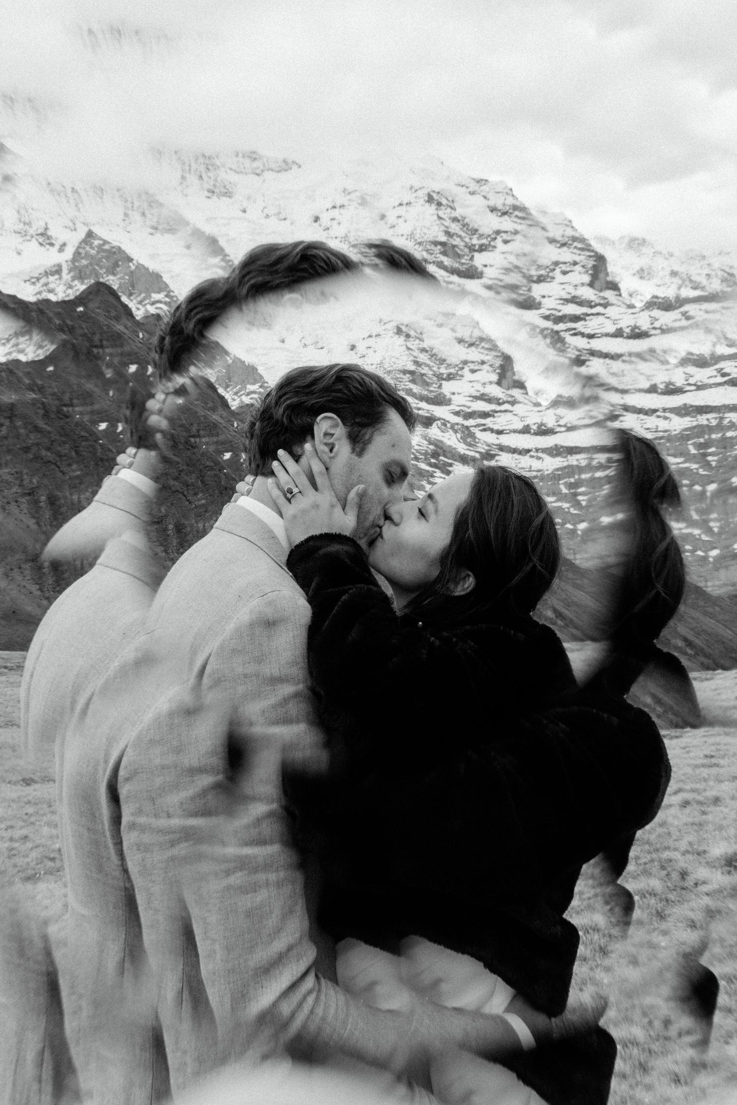 Black and white photo of an intimate moment with snow-capped mountains in the background.